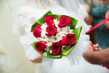 Bride and groom's hands with wedding flowers . Bride and groom hands with wedding flowers and bridal dress .
