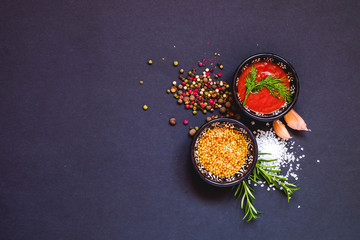 Various herbs and spices on dark background, top view