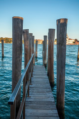 Pier wooden poles tightened together by rusty chains on canal in Venice