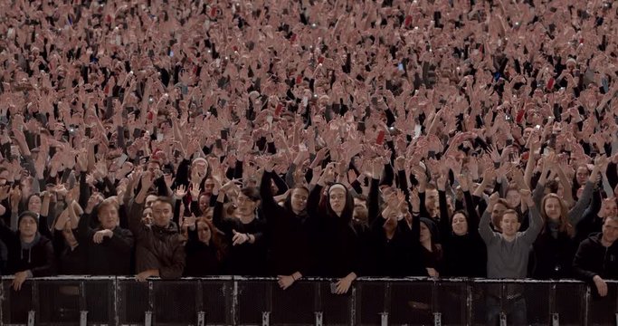 Model released, Front view of huge crowd dancing and cheering at a concert or a show behind control barrier. Shot on RED Helium 8K Prores 4444