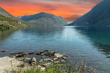 Mountain lake landscape with red sunset sky, Norway, road to Dalsnibba mountain from Geiranger.
