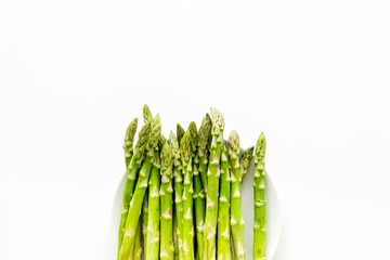 Fresh asparagus on plate on white background top-down copy space