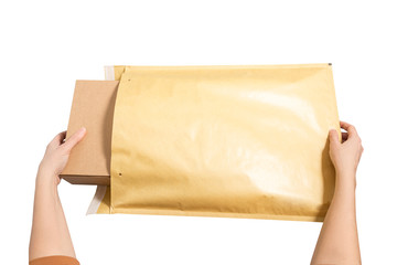 Woman hands puting  cardboard box inside of large postal envelope