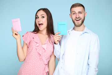 Happy young couple holding passports on blue background