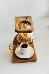 Creative art handmade lamp made of drip coffee station, v60 dripper and lights. Cup of black coffee in the lower board. Idea for coffee shop interior