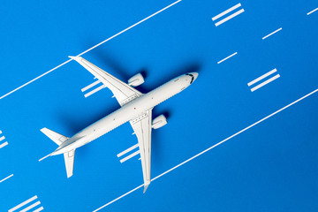 The passenger plane on airport runway and blue background. Top view, Travel and adventure concept