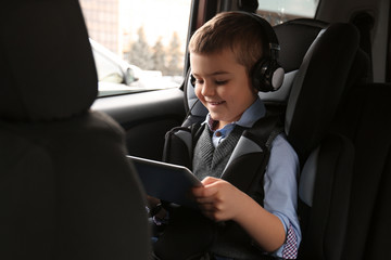 Cute little boy listening to audiobook in car