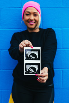 Woman Holding Sonogram On Colorful Wall - Baby Gender Reveal