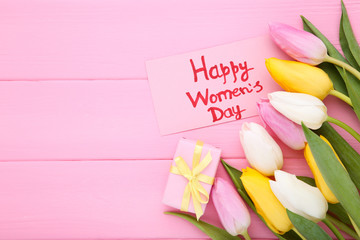 Text Happy Womens Day with tulip flowers and gift box on wooden table