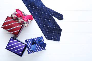 Blue necktie with gift boxes on white wooden table