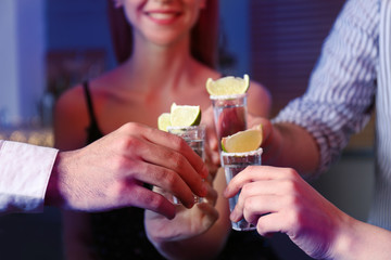 Young people toasting with Mexican Tequila shots at bar, closeup