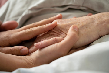 Close-up of home carer consoling senior female patient at nursing home