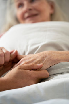 Close-up of home carer consoling senior female patient at nursing home
