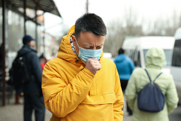 Asian man wearing medical mask on city street. Virus outbreak