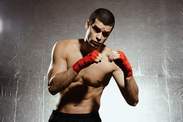 Fototapeta na wymiar Athletic boxer punching with determination and precaution over silver kground