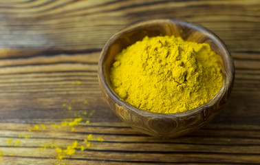 Turmeric powder in a wooden bowl on a wooden background. Turmeric close -up. Banner with a copy of the place .
