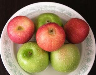 red and green apples in drops of water on a plate