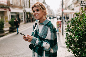 Attractive stylish young woman wearing stripped shirt walking on the old europe city with smartphone and enjoy her trip