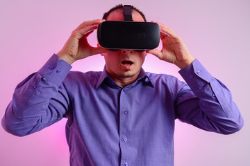 Front view of  man with glasses of virtual reality. Future technology concept. Modern imaging technology.  Isolated on neon light background. VR headset.