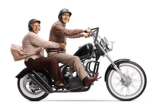Cheerful senior man and woman riding a custom motorbike and smiling at the camera