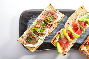 Bruschetta with baked pepper, tuna, avocado and pastrami