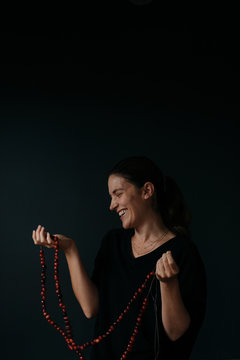 woman holding cranberry garland against a dark background with renaissance lighting