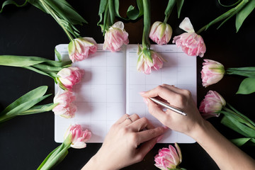 Top view of diary with roses. Female writing in her diary with roses