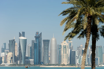 Plakat Panoramic view of modern skyline of Doha through blurred palm trees. Qatar on sunny day