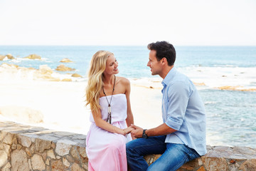 Young couple sitting near the ocean at a resort