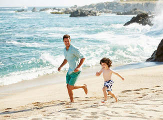 Father and son running on the beach on vacation in Mexico