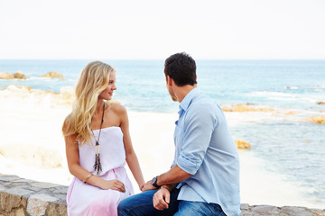 Young couple sitting along the ocean at a resort