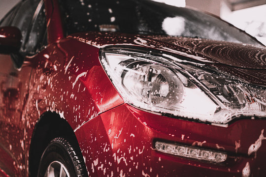 Automovil rojo siendo lavado en un lavadero CARWASH