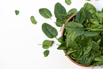 Fresh spinach in a wooden bowl isolated on white background top view photo