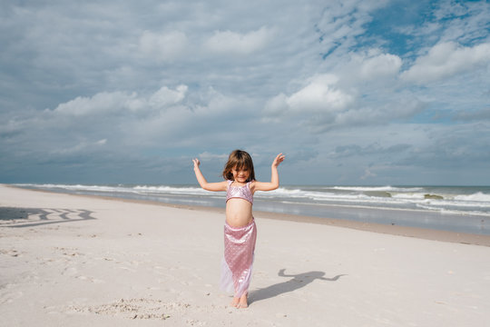 little girl posing in mermaid bathing suit on beach