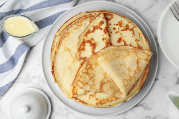 Flat lay composition with fresh thin pancakes on white marble table