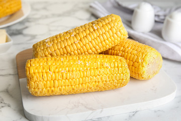 Delicious boiled corn with salt on white marble table