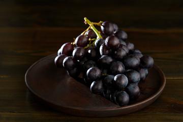 Dark purple grape on wooden plate. Vintage wooden table, high resolution
