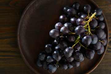 Dark purple grape on wooden plate. Vintage wooden table, high resolution