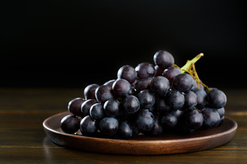 Dark purple grape on wooden plate. Vintage wooden table, high resolution