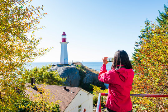 Woman take photo of lighthouse at Lighthouse Park, West Vancouve