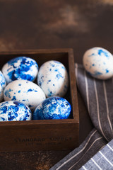 Dyed Easter eggs. Сlassic blue Easter eggs on the grey background. Blue speckled easter eggs with paint and brushes. Decorating eggs, preparing for Easter