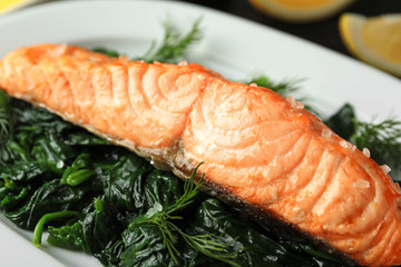Tasty salmon with spinach on plate, closeup
