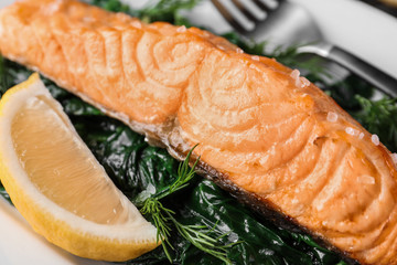 Tasty salmon with spinach and lemon, closeup