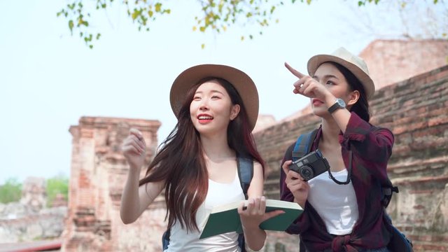 Two Asian female walk and take a picture in the archaeological site together at Ayutthaya Province, Thailand.
