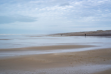 Caux. Somme. France. plage de sable à marée basse. Des personnes au loin se promènent sur le sable.