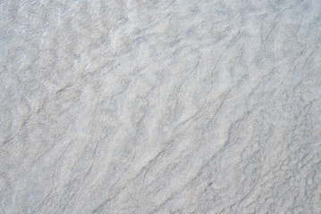 Gros plan sur des mini dunes de sable gris sur une plage à marée basse, ondulations sablonneuse.s