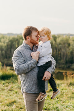 Loving father holds his son on the hands, touches the cheeks and close eyes