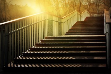 Staircase with a shadow. Sunlight on a staircase with wooden steps and metal railing. A play of light and shadow in the evening.