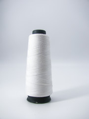bobbin with white sewing threads on a light background