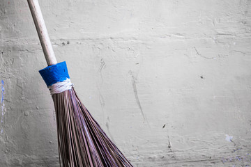 Traditional stick brooms are leaning against a pale yellow concrete wall. Vintage theme background concept.
